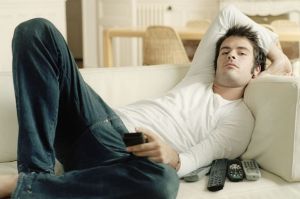 Man-relaxing-on-sofa-holding-remote-controls